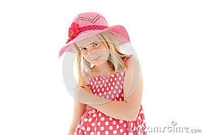 Beautiful young blonde girl with enigmatic smile wearing big pink floppy hat and a polka dot dress. Isolated on white studio Stock Photo