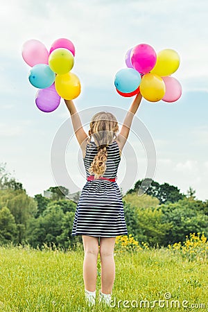 Beautiful young blonde girl smiles on a summer day walks with colored balls in the city Stock Photo