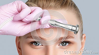 Beautiful young blonde woman with makeup,clean fresh skin naked shoulders holds a nozzle for microdermabrasion in her hands. Stock Photo
