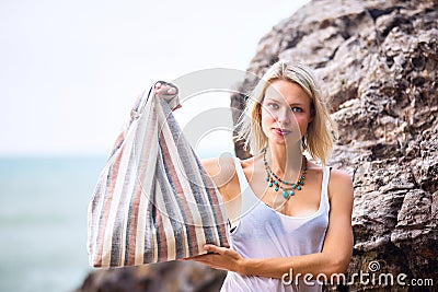 Beautiful young blonde woman posing outdoor at the rocky sea shore Stock Photo