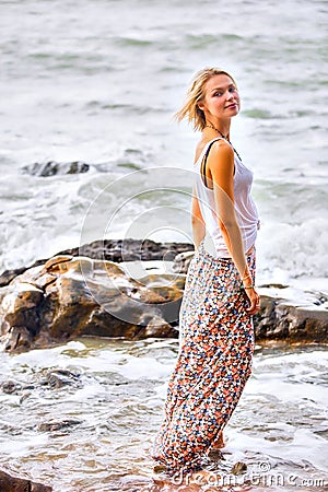 Beautiful young blonde woman posing outdoor at the rocky sea shore Stock Photo