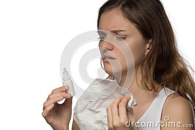 A beautiful brunette woman gets sick and a runny nose, digs her nose with medicine and holds a white paper kerchief Stock Photo