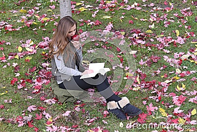 Beautiful young caucasian blonde eating an apple, reading a book Stock Photo