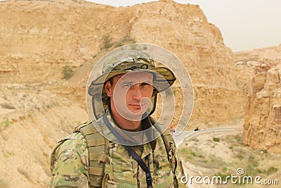 Beautiful young caucasian soldier in universal camouflage uniform on a background of a rocks. Military concept, copy space. Jordan Stock Photo