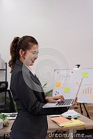 Beautiful young concentration business woman using laptop while standing in office Stock Photo