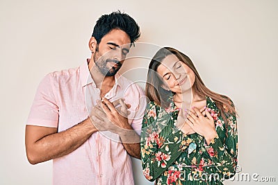 Beautiful young couple of boyfriend and girlfriend together smiling with hands on chest with closed eyes and grateful gesture on Stock Photo