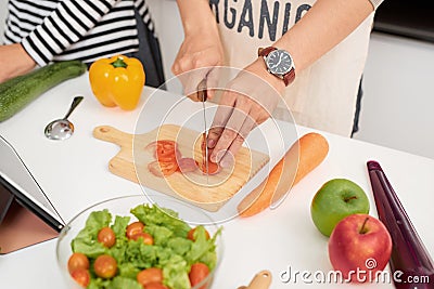 Beautiful young couple is cooking in kitchen at home.Man is cooking with Moman is using a digital tablet and smiling Stock Photo