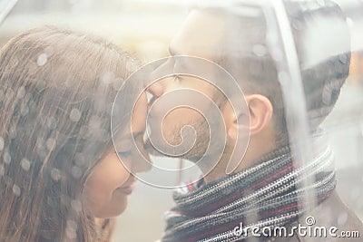 Beautiful young couple having a romantic tender moment under the rain - Handsome man kissing his girlfriend forehead Stock Photo