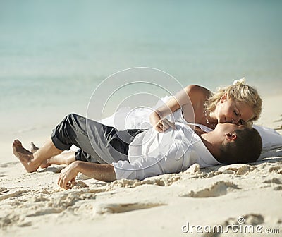 Beautiful young couple kissing on sunset lying on sand, sunset t Stock Photo