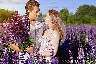 A beautiful couple in love on a blooming field with a bouquet of bright flowers Stock Photo