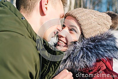 Beautiful young couple in love hugging in the park on a clear sunny winter day, close up. Boy and girl smile at each other Stock Photo