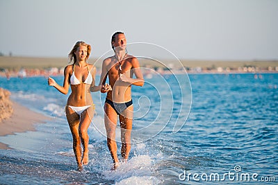 Beautiful young couple runnung at sea water edge and holding hands Stock Photo