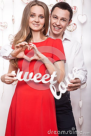 Beautiful young couple with words Sweet love showing the form of heart hands. Valentine's Day. Stock Photo