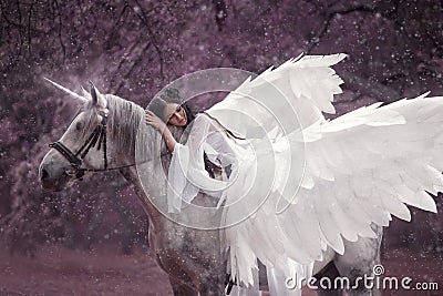 Beautiful, young elf, walking with a unicorn. She is wearing an incredible light, white dress. Art hotography Stock Photo
