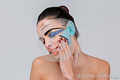 A girl with geometric make-up closed eyes and holds hand near the cheek. On a gray background. Stock Photo