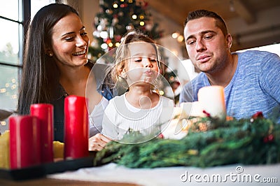 Young family blowing candles on advent wreath. Stock Photo