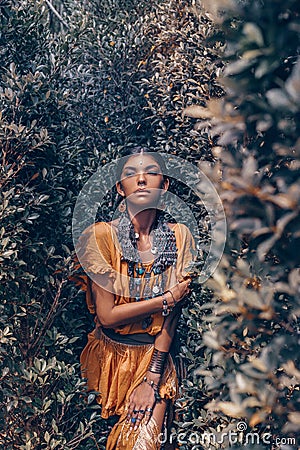 Beautiful young fashionable woman with make up and stylish boho accessories posing on natural tropical background Stock Photo