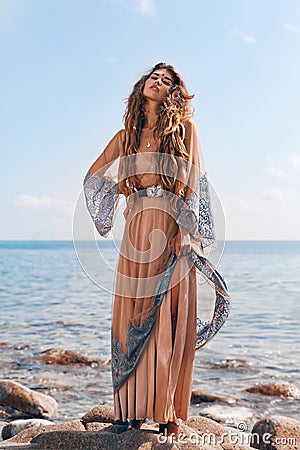 Beautiful young fashionable woman at the stone beach at sunset Stock Photo