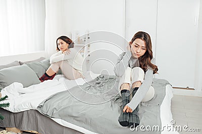 Beautiful young female friends having serious quarrel and feeling angry ignore each other in bedroom Stock Photo