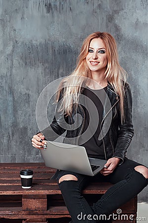 Beautiful young female girl using portable laptop computer while sitting in a vintage place and drinking coffee. Stock Photo