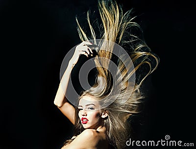 Beautiful young female model with long lush hair fluttering in wind naked back in studio on black background. Stock Photo
