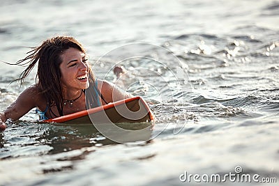 Beautiful young female surfer swimming on surfboard, smiling. copy space Stock Photo