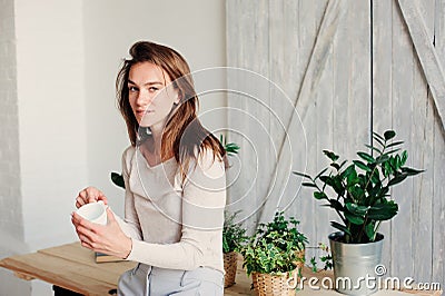 Beautiful young feminine woman relaxing at home in lazy weekend morning with cup of coffee Stock Photo