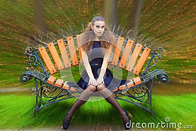 Beautiful young girl autumn day on the street with fantasy makeup in a black dress with big lips sitting on a bench Stock Photo