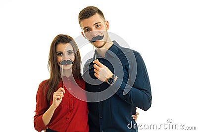 Beautiful young girl and boy look right and keep near their faces paper black whiskers Stock Photo