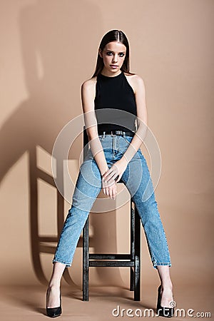 Beautiful young girl with brown long hair sits on high chai Stock Photo