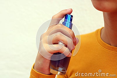 Beautiful young girl dressed in yellow, spraying perfume Stock Photo