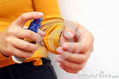 Beautiful young girl dressed in yellow, spraying perfume Stock Photo