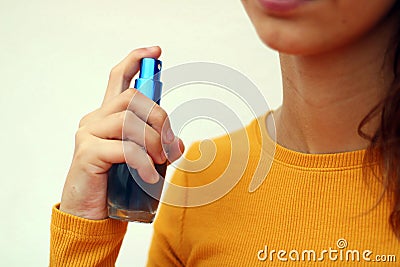 Beautiful young girl dressed in yellow, spraying perfume Stock Photo