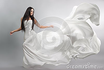 Beautiful young girl in flying white dress. Flowing fabric. Light white cloth flying Stock Photo