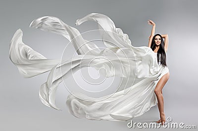 Beautiful young girl in flying white dress. Flowing fabric. Light white cloth flying Stock Photo