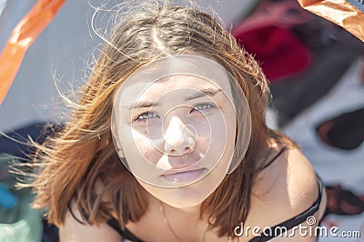 Beautiful young girl with freckles looking at the camera. Portrait of a girl with brown hair in nature. Stock Photo