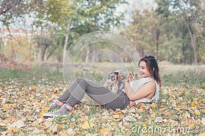 Beautiful young girl with her Yorkshire terrier dog puppy enjoying in the autumn day in the park selective focus Stock Photo