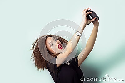 Beautiful young girl hipster takes photos, shoots selfe, taking pictures of himself on camera in jeans and a black t-shirt Stock Photo