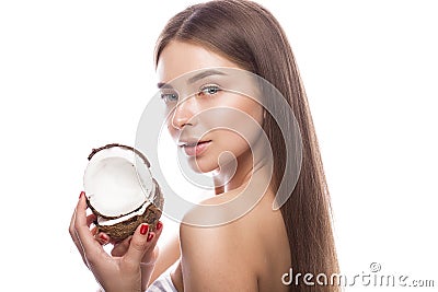 Beautiful young girl with a light natural make-up and perfect skin with coconut in her hand . Beauty face. Stock Photo