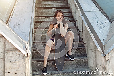 Beautiful young girl with a long board in the city. The concept of modern youth. Active fun holiday. Stock Photo