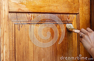 Beautiful young girl paints a wooden door. Summer work in the garden Stock Photo