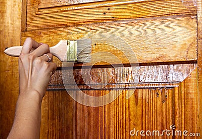Beautiful young girl paints a wooden door. Summer work in the garden Stock Photo