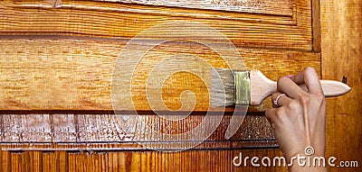 Beautiful young girl paints a wooden door. Summer work in the garden Stock Photo