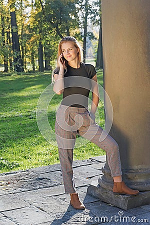 Beautiful young girl is phoning standing in autumn park Stock Photo