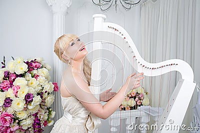 Beautiful young girl portrait in spring flowers playing the harp Stock Photo