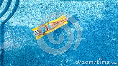 Beautiful young girl relaxing in swimming pool, swims on inflatable mattress and has fun in water on family vacation Stock Photo