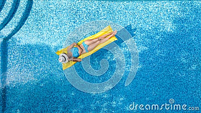 Beautiful young girl relaxing in swimming pool, swims on inflatable mattress and has fun in water on family vacation Stock Photo