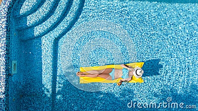 Beautiful young girl relaxing in swimming pool, swims on inflatable mattress and has fun in water on family vacation Stock Photo