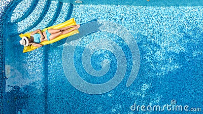 Beautiful young girl relaxing in swimming pool, swims on inflatable mattress and has fun in water on family vacation Stock Photo