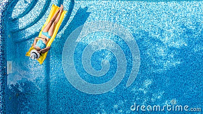 Beautiful young girl relaxing in swimming pool, swims on inflatable mattress and has fun in water on family vacation Stock Photo